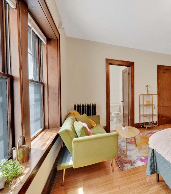A bedroom with a bed, a chair, and a window.