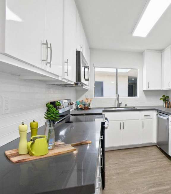 A modern kitchen with a stainless steel refrigerator and white cabinets.