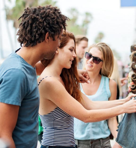 people looking at a pair of jeans at an outdoor market