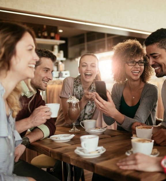 a group of people sitting around a table talking and laughing