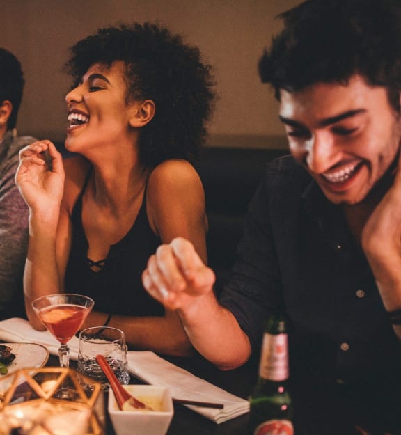 a group of people sitting at a table laughing and eating at a restaurant