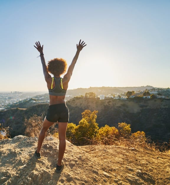 a woman standing on a rock with her hands in the air