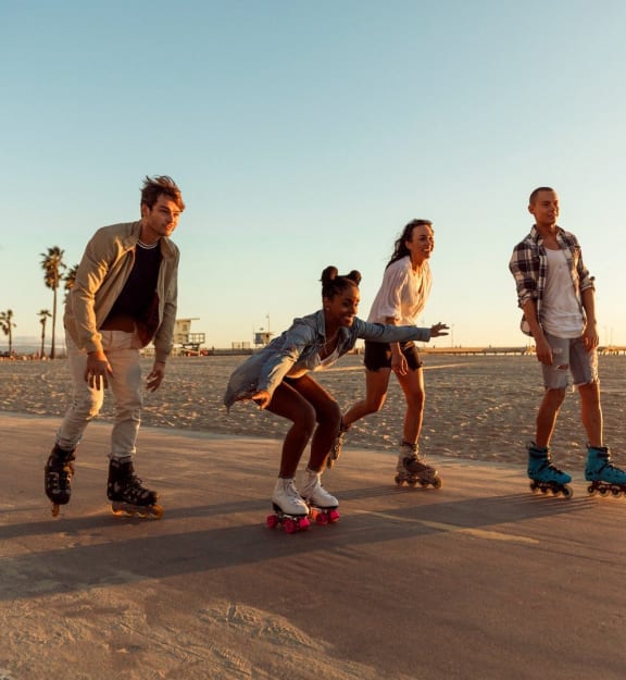 a group of people riding skateboards on the beach