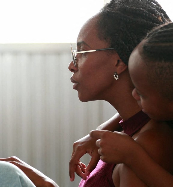 a woman holding a child in front of a laptop computer