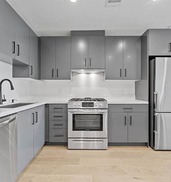 A modern kitchen with stainless steel appliances and grey cabinets.