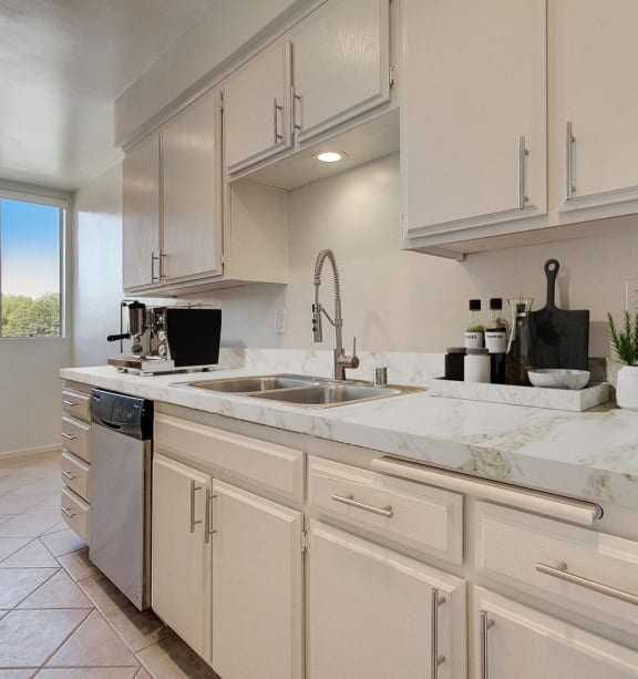 an open kitchen with white cabinets and marble counter tops and a sink