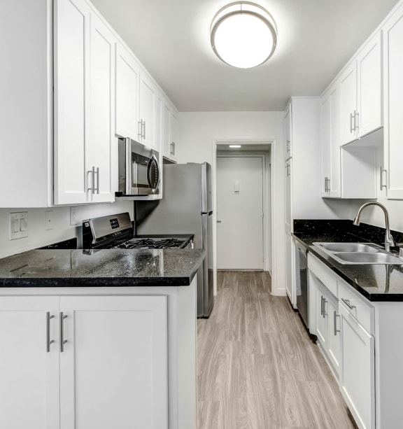 a white kitchen with white cabinets and black counter tops