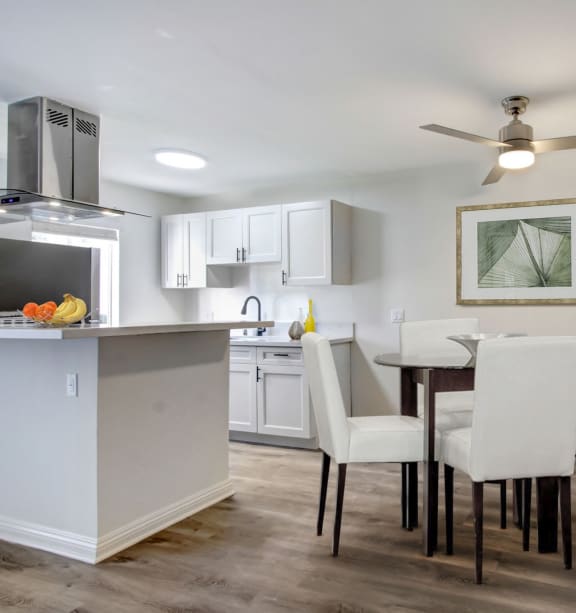 a kitchen and dining room with white chairs and a glass table