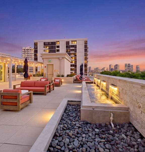 A rooftop patio with a water feature and seating area.