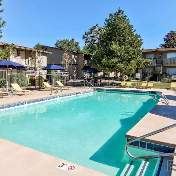 A swimming pool with a slide and a building in the background.