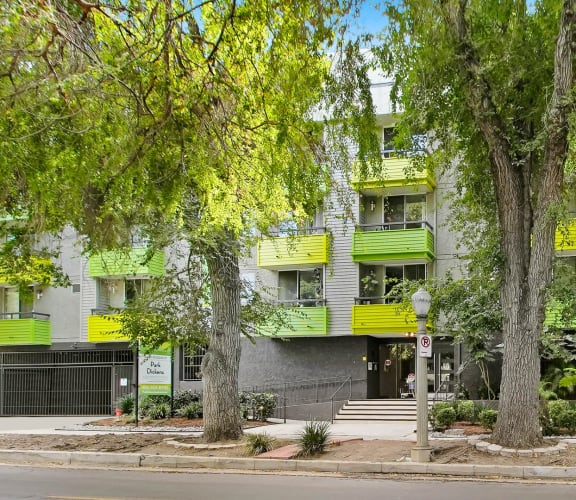 a building with green balconies and trees in front of it