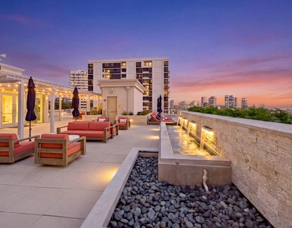 A rooftop patio with a water feature and seating area.
