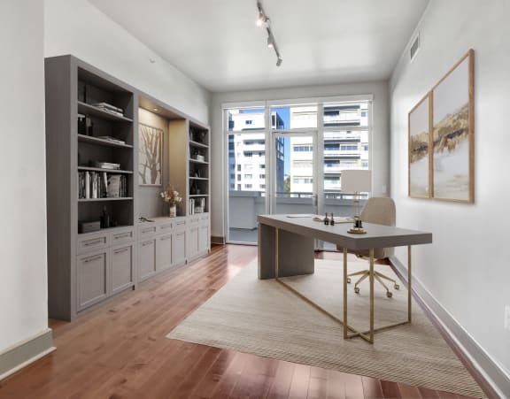 a home office with a large window and a desk with a rug