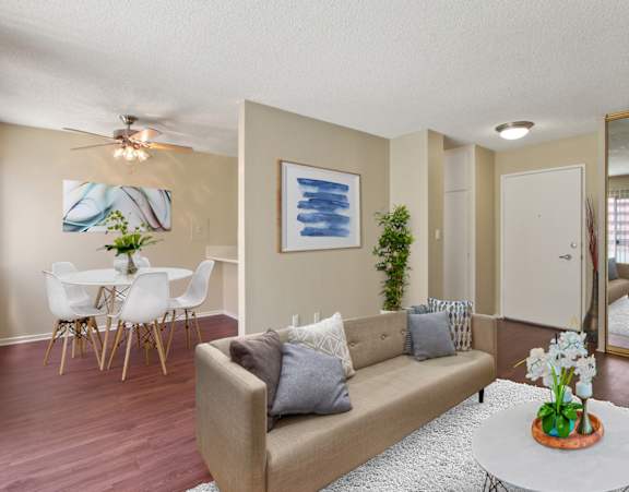 A living room with a couch, a dining table, and a painting on the wall.