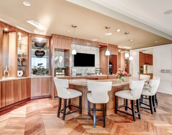 a kitchen with a large island with bar chairs and a tv