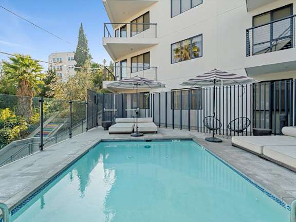 A swimming pool in a residential area with a white building in the background.