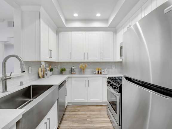 the kitchen has stainless steel appliances and white cabinets