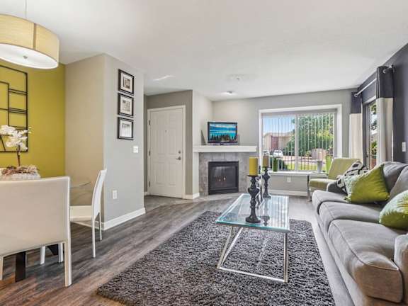 A modern living room with a glass coffee table and a grey sofa.