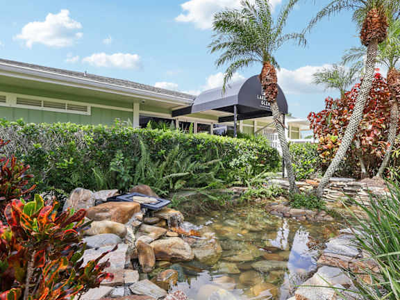 A garden with a pond and a house in the background.