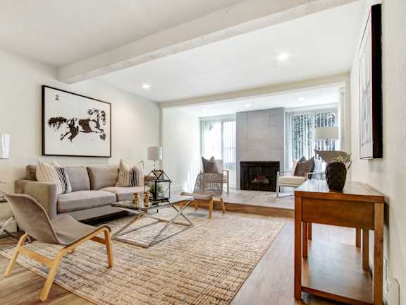 A living room with a grey couch, a wooden table, and a painting on the wall.