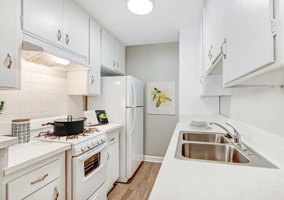 A white kitchen with a stove, sink, and refrigerator.