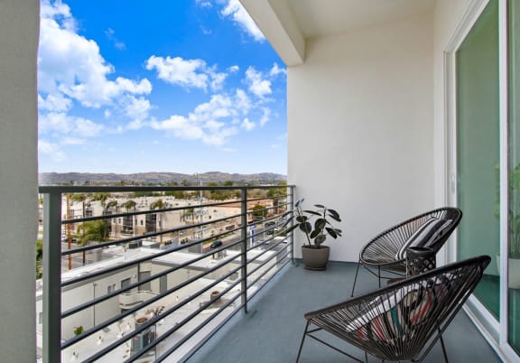 a balcony with two chairs and a plant