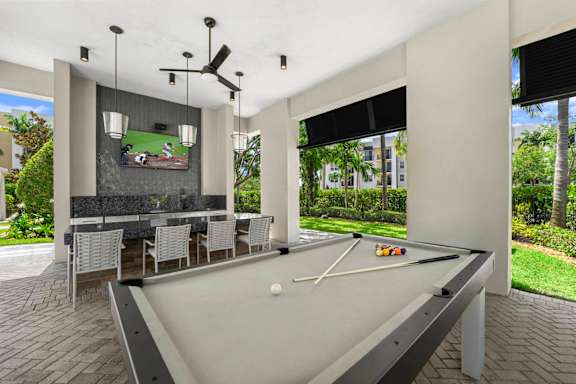 A pool table with a ball on it and a tv screen on the wall.