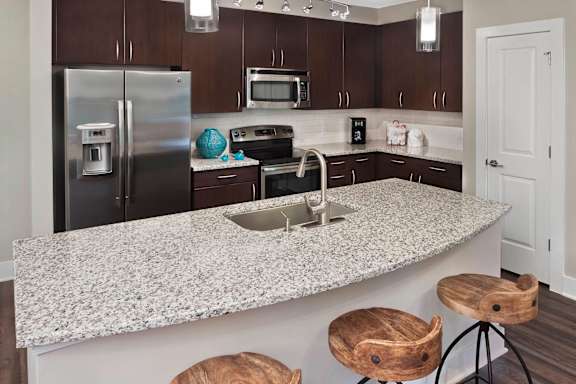 A kitchen with a granite countertop and wooden bar stools.