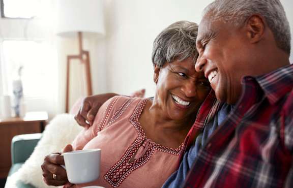 a man and a woman laughing while sitting on a couch