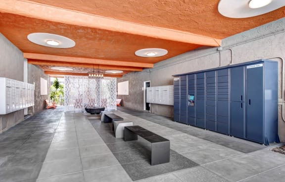 a long hallway with blue lockers and a row of benches