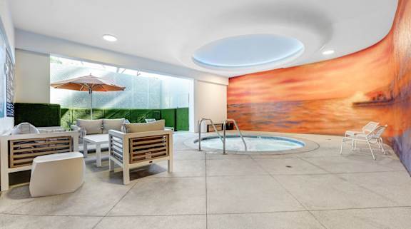 A modern outdoor seating area with a pool and a mural on the wall.