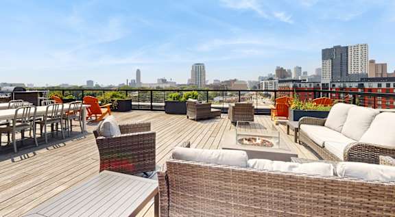 A rooftop patio with a table and chairs overlooking a city skyline.