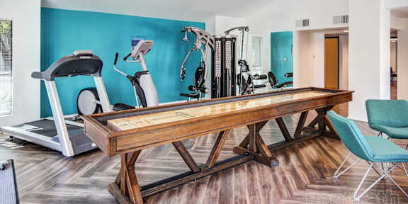 A gym with a treadmill, elliptical trainer, and other exercise equipment.