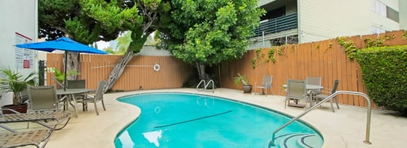 a swimming pool with chairs and umbrellas in front of a building