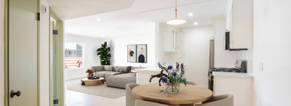 a renovated kitchen and living room with white walls and wood floors