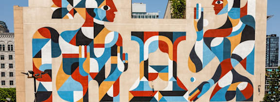 A large mural of a woman's face is painted on a building.