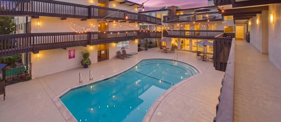 A large outdoor swimming pool surrounded by a patio area with lights strung above.