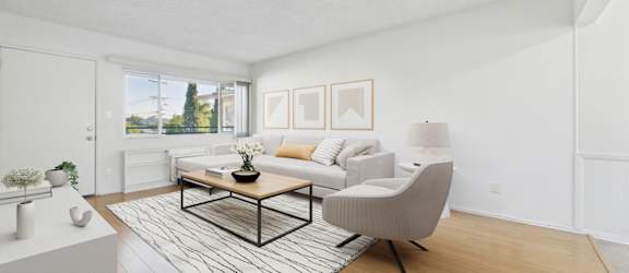 A black chair sits next to a grey couch with a glass coffee table in between.