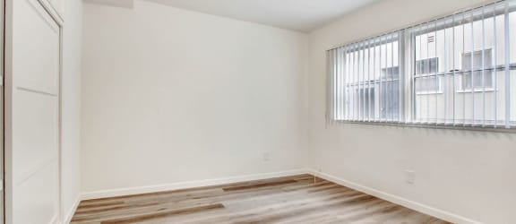 a bedroom with hardwood flooring and a large window