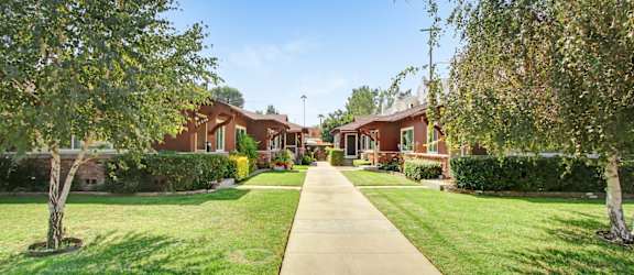 a sidewalk in front of houses with grass and trees
