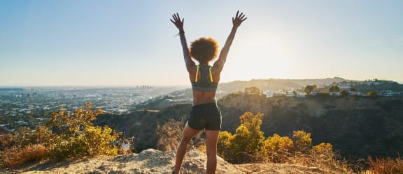 a woman standing on a rock with her hands in the air