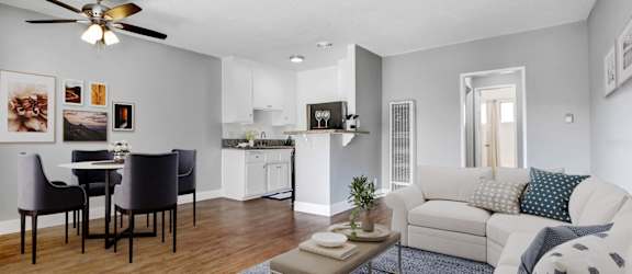 A living room with a white couch and a dining table with chairs.