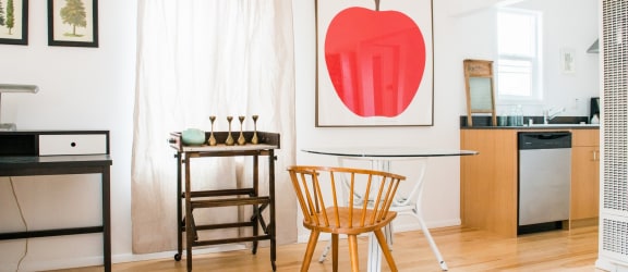 a dining room with a table and chairs and a painting of an apple