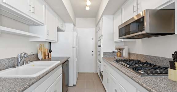 a kitchen with white cabinets and granite counter tops and a stove and microwave