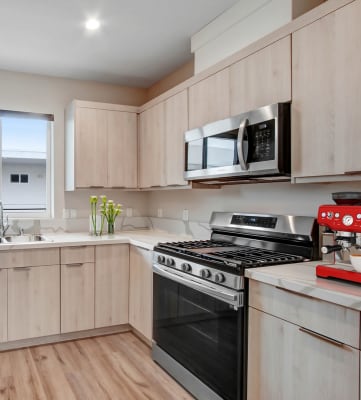 a kitchen with light wood cabinets and stainless steel appliances