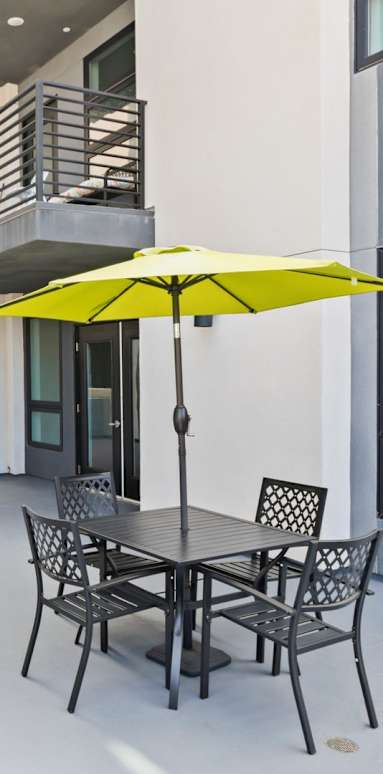 a patio with a table and chairs and a yellow umbrella