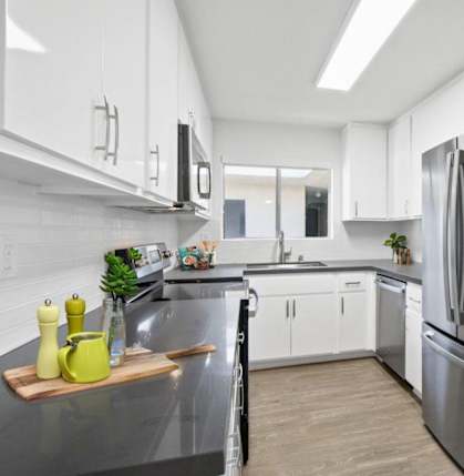 A modern kitchen with a stainless steel refrigerator and white cabinets.