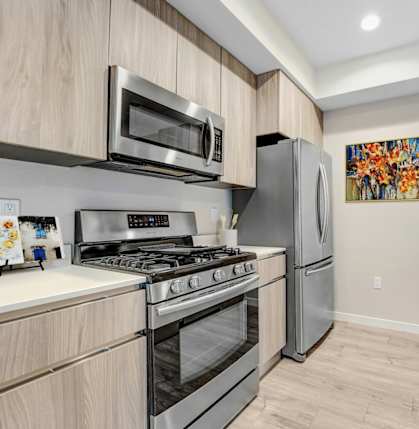 A modern kitchen with a stainless steel refrigerator, microwave, and oven.at The Blvd Lofts, Encino, CA