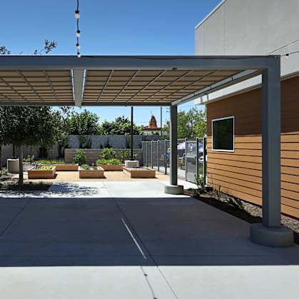 A patio with a white pergola and concrete floor.