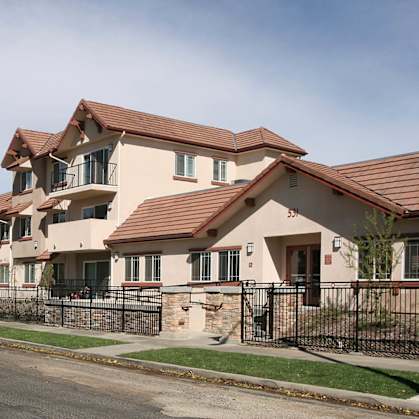 A row of houses with brown roofs and black fences.